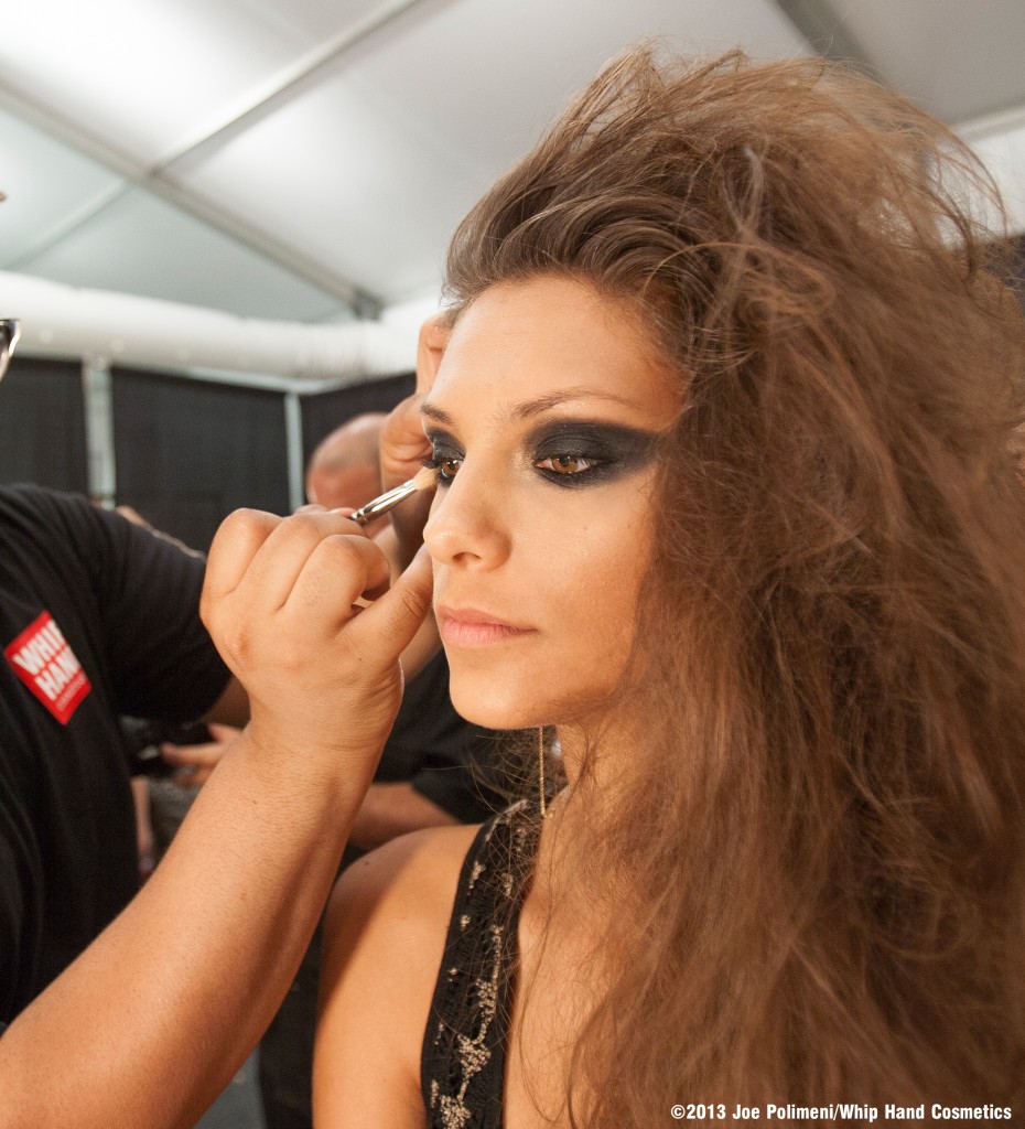Whip Hand Cosmetics Lead Makeup Artist Victor Amos applies eyeshadow backstage to model Fernanda Uesler.